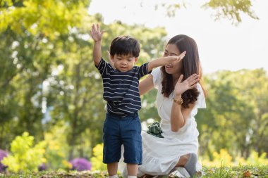 Mutlu Asyalı bir aile, annesi ve oğlu parkta oynarken eğleniyor.