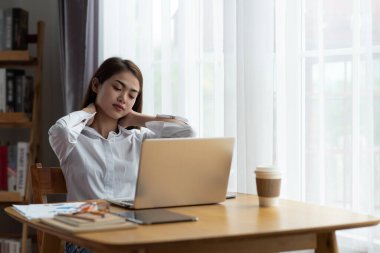 Ofiste boynu ağrıyan Asyalı genç iş kadını.