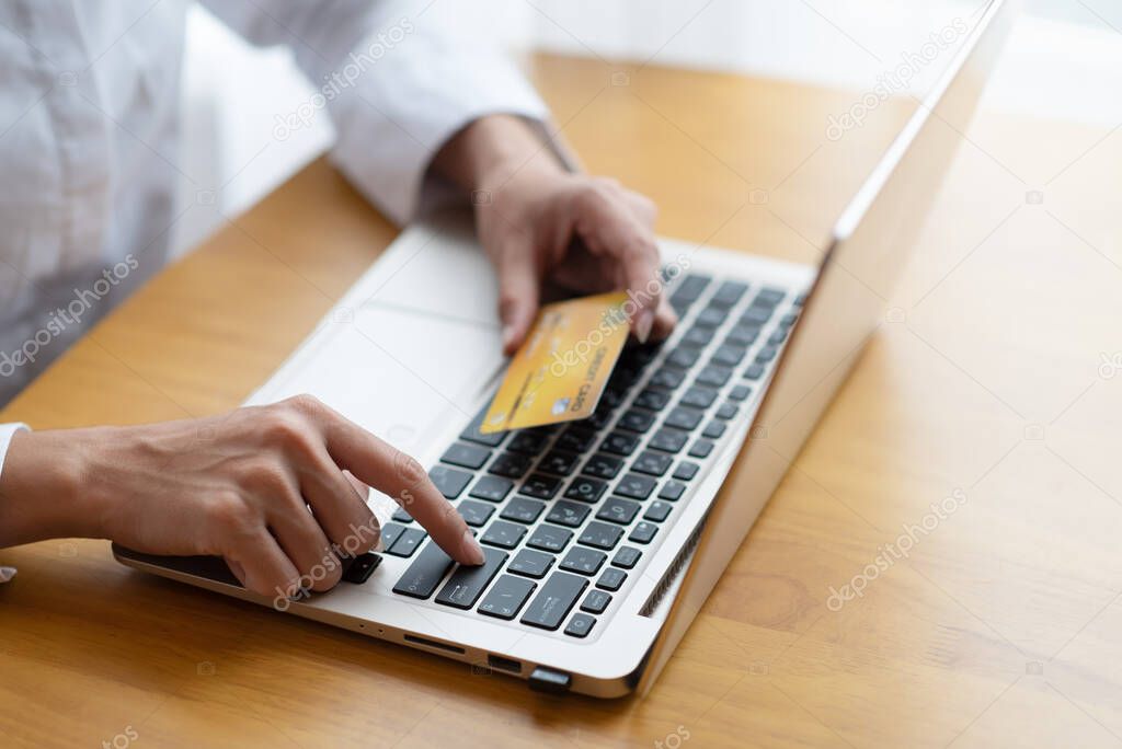 Close-up of woman holding credit card and using laptop for online shopping