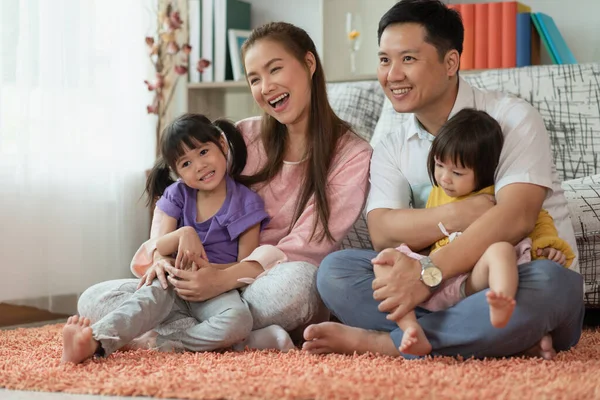 Happy Asian family mother and father with two daughters playing together at home