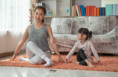 Anne ve kızı evde yoga egzersizleri yapıyor. Mutlu Asyalı aile sevgisi kavramı.