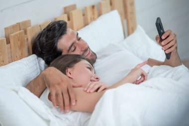 Mutlu ve rahat bir çift cep telefonu kullanıyor ve gülümsüyor.