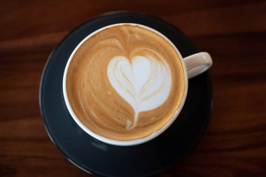 Tahta masada bir fincan sıcak latte sanat kahvesi.