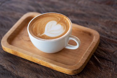 Tahta masada bir fincan sıcak latte sanat kahvesi.