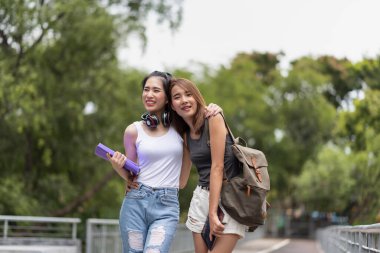 Kampüste yürürken konuşan iki genç Asyalı üniversite öğrencisi.