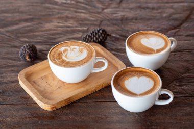 Tahta masada bir fincan sıcak latte sanat kahvesi.