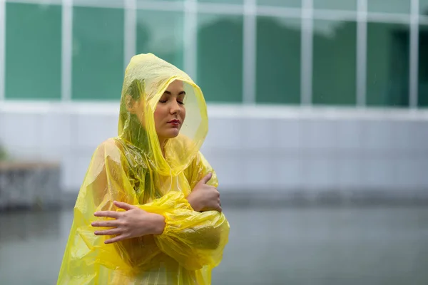 Portrait of the women wearing yellow raincoat while raining in rainy season