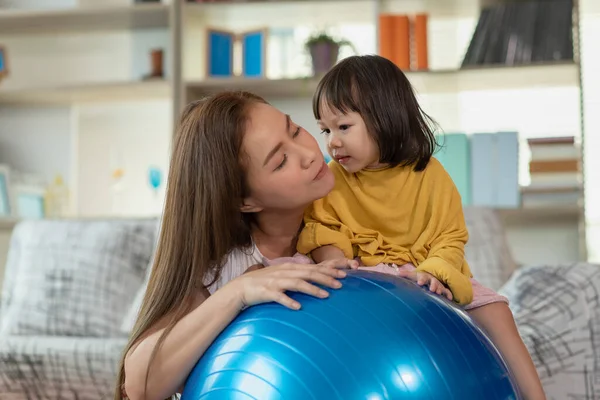 幸せなアジアの子供は体操ボールを楽しんで 自宅で母親と一緒に練習をしています — ストック写真