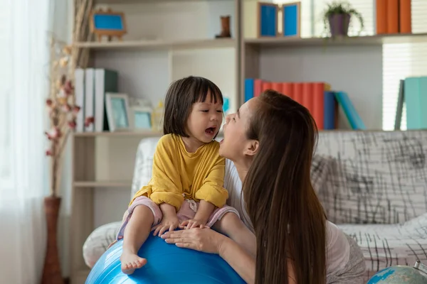 幸せなアジアの子供は体操ボールを楽しんで 自宅で母親と一緒に練習をしています — ストック写真