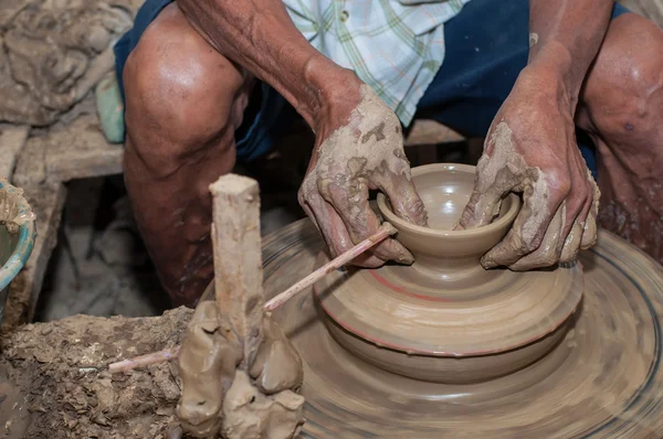 A man shapes pottery as it turns on a wheel — Stock Photo, Image