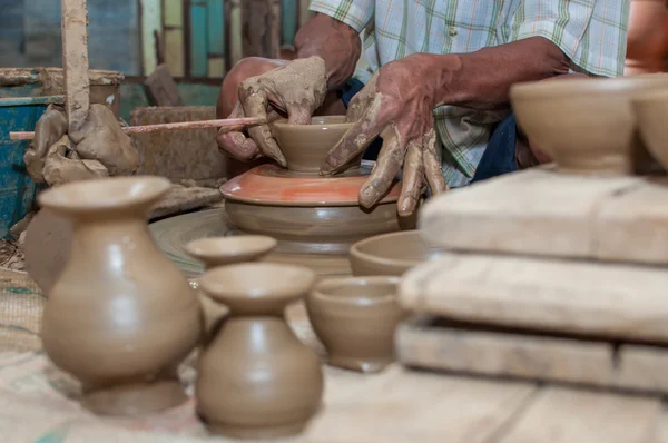 A man shapes pottery as it turns on a wheel