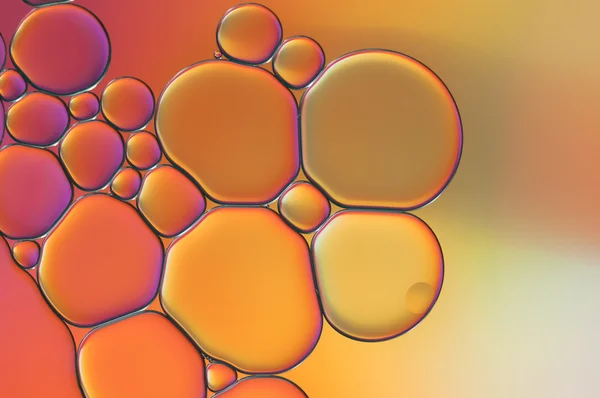 Rosa und orangefarbene Tropfen Öl und Luftblasen auf dem Wasser — Stockfoto