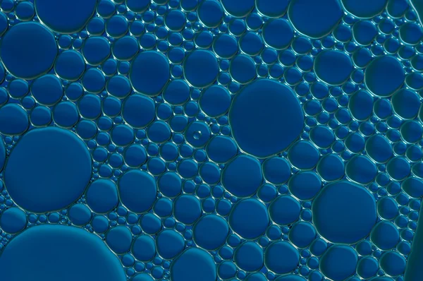Blauwe druppels olie en lucht bubbels op het water — Stockfoto