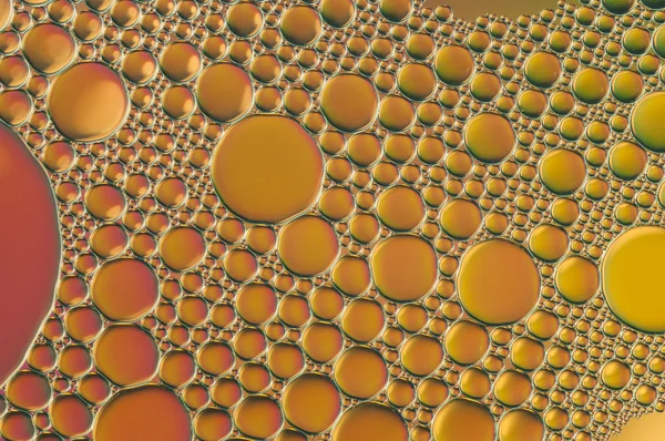 Violette und orangefarbene Tropfen Öl und Luftblasen auf dem Wasser — Stockfoto