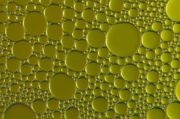 Gyllene droppar av olja och luft bubblor på vattnet — Stockfoto