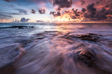 Deniz dalgaları plajda kayaya çarpıyor.