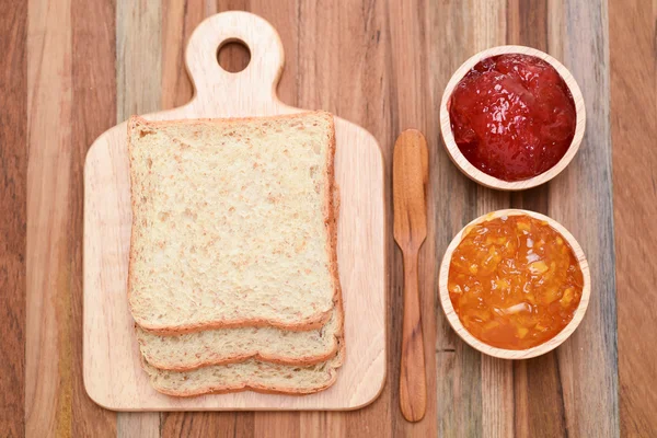 Slices bread with jam on wooden table — Stock Photo, Image