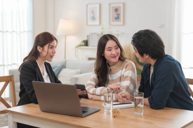 Asyalı finans danışmanı ofisteki genç çifte yeni proje yatırımını açıklıyor. Emlakçı aileyle ipotek seçeneklerini tartışıyor. Finans danışmanıyla ipotek kredisi danışmanlığı.