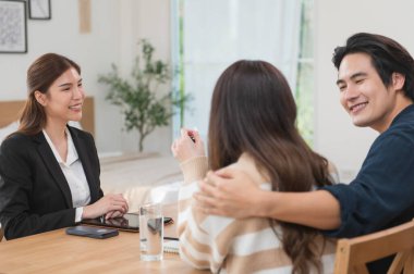 Asyalı finans danışmanı ofisteki genç çifte yeni proje yatırımını açıklıyor. Emlakçı aileyle ipotek seçeneklerini tartışıyor. Finans danışmanıyla ipotek kredisi danışmanlığı.