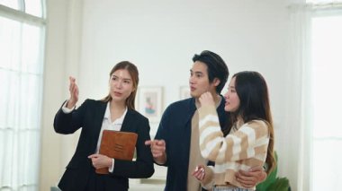 Asyalı finans danışmanı ofisteki genç çifte yeni proje yatırımını açıklıyor. Emlakçı aileyle ipotek seçeneklerini tartışıyor. Finans danışmanıyla ipotek kredisi danışmanlığı.