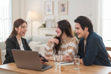 Asyalı finans danışmanı ofisteki genç çifte yeni proje yatırımını açıklıyor. Emlakçı aileyle ipotek seçeneklerini tartışıyor. Finans danışmanıyla ipotek kredisi danışmanlığı.