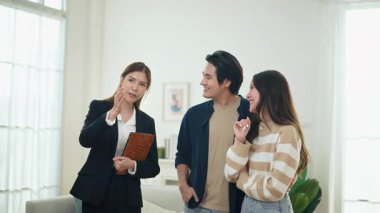 Asyalı finans danışmanı ofisteki genç çifte yeni proje yatırımını açıklıyor. Emlakçı aileyle ipotek seçeneklerini tartışıyor. Finans danışmanıyla ipotek kredisi danışmanlığı.