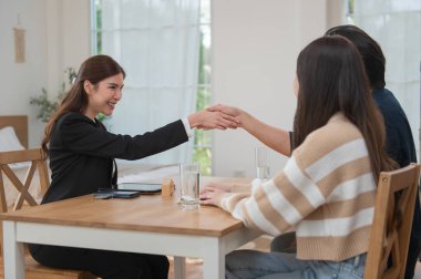 Asyalı finans danışmanı ofisteki genç çifte yeni proje yatırımını açıklıyor. Emlakçı aileyle ipotek seçeneklerini tartışıyor. Finans danışmanıyla ipotek kredisi danışmanlığı.