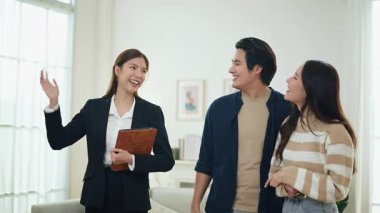 Asyalı finans danışmanı ofisteki genç çifte yeni proje yatırımını açıklıyor. Emlakçı aileyle ipotek seçeneklerini tartışıyor. Finansal konut kredisi danışmanlığı