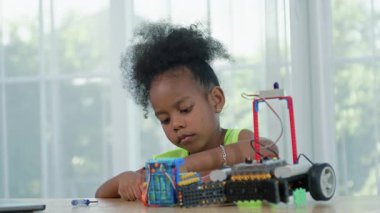 Genç Afrikalı kız mühendis STEM eğitim sınıfında robotik projesinde çalışıyor. Çocuk, küçük bir robot ya da elektronik projeyi birleştirmeye ve öğrenmeye odaklanmıştır. yenilik, teknoloji.