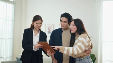 Asyalı finans danışmanı ofisteki genç çifte yeni proje yatırımını açıklıyor. Emlakçı aileyle ipotek seçeneklerini tartışıyor. Finans danışmanıyla ipotek kredisi danışmanlığı.