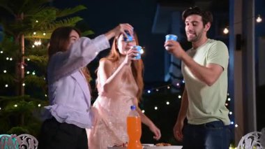 Açık Hava Gece Partisi 'nde Dans ve İçki İçen Çeşitli Arkadaş Grubu. Sahne dekoratif sicim lambalarıyla aydınlatılıyor ve neşeli bir atmosfere sahip. Hafta sonları ya da tatillerde eğlence.