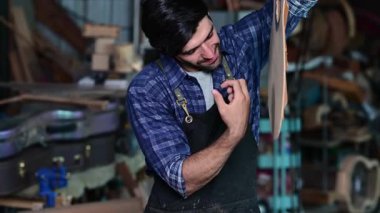 Luthier gitar yapıyor ve el aletleriyle çalışma odasında geleneksel aletler kullanıyor.