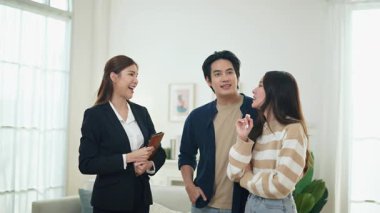 Asyalı finans danışmanı ofisteki genç çifte yeni proje yatırımını açıklıyor. Emlakçı aileyle ipotek seçeneklerini tartışıyor. Finans danışmanıyla ipotek kredisi danışmanlığı.