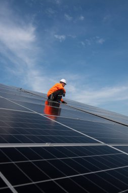 Teknisyen yeşil enerji için fabrikanın çatısına güneş panelleri kuruyor. Güvenlik teçhizatı konusunda yetenekli bir teknisyen çatıdaki bir güneş paneli tesisi üzerinde çalışıyor. Temiz enerji yenilenebilir enerji teknolojisi.