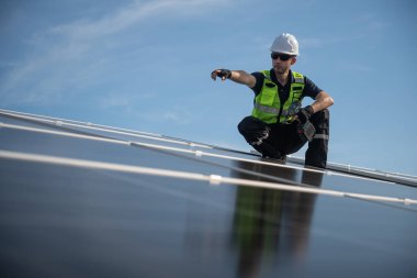 Teknisyen yeşil enerji için fabrikanın çatısına güneş panelleri kuruyor. Güvenlik teçhizatı konusunda yetenekli bir teknisyen çatıdaki bir güneş paneli tesisi üzerinde çalışıyor. Temiz enerji yenilenebilir enerji teknolojisi.