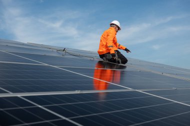 Teknisyen yeşil enerji için fabrikanın çatısına güneş panelleri kuruyor. Güvenlik teçhizatı konusunda yetenekli bir teknisyen çatıdaki bir güneş paneli tesisi üzerinde çalışıyor. Temiz enerji yenilenebilir enerji teknolojisi.