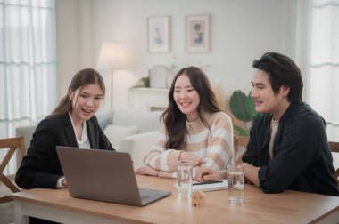 Asyalı finans danışmanı ofisteki genç çifte yeni proje yatırımını açıklıyor. Emlakçı aileyle ipotek seçeneklerini tartışıyor. Finans danışmanıyla ipotek kredisi danışmanlığı.