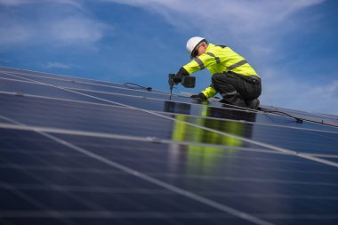 Teknisyen yeşil enerji için fabrikanın çatısına güneş panelleri kuruyor. Güvenlik teçhizatı konusunda yetenekli bir teknisyen çatıdaki bir güneş paneli tesisi üzerinde çalışıyor. Temiz enerji yenilenebilir enerji teknolojisi.