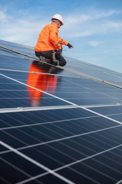 Teknisyen yeşil enerji için fabrikanın çatısına güneş panelleri kuruyor. Güvenlik teçhizatı konusunda yetenekli bir teknisyen çatıdaki bir güneş paneli tesisi üzerinde çalışıyor. Temiz enerji yenilenebilir enerji teknolojisi.