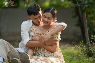 Asyalı genç çift birbirine bakıyor ve sarılıyorlar, erkek ve kadın birlikte vakit geçiriyorlar..