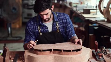 Luthier, el aletleri, sanat ve el sanatları konseptiyle çalışma odasında geleneksel aletleri kullanarak gitarın tepesini yapıyor..