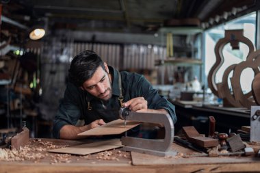 Luthier, el aletleri, sanat ve el sanatları konseptiyle çalışma odasında geleneksel aletleri kullanarak gitarın tepesini yapıyor..