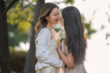 Mutlu Asyalı lezbiyen lgbtq çifti birbirini öpüyor, birlikte zaman geçiriyorlar..