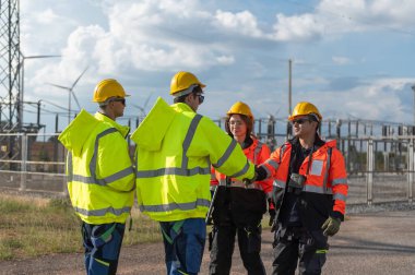 Elektrik santralinde çalışan mühendisler. Bir rüzgar türbini çiftliğindeki elektrik santralini denetleyen güvenlik kaskı takan teknisyen, elektrik ve sanayi çevresi için eko teknolojisi.