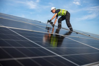 Teknisyen yeşil enerji için fabrikanın çatısına güneş panelleri kuruyor. Güvenlik teçhizatı konusunda yetenekli bir teknisyen çatıdaki bir güneş paneli tesisi üzerinde çalışıyor. Temiz enerji yenilenebilir enerji teknolojisi.