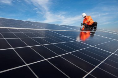 Teknisyen yeşil enerji için fabrikanın çatısına güneş panelleri kuruyor. Güvenlik teçhizatı konusunda yetenekli bir teknisyen çatıdaki bir güneş paneli tesisi üzerinde çalışıyor. Temiz enerji yenilenebilir enerji teknolojisi.