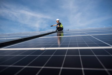 Teknisyen yeşil enerji için fabrikanın çatısına güneş panelleri kuruyor. Güvenlik teçhizatı konusunda yetenekli bir teknisyen çatıdaki bir güneş paneli tesisi üzerinde çalışıyor. Temiz enerji yenilenebilir enerji teknolojisi.