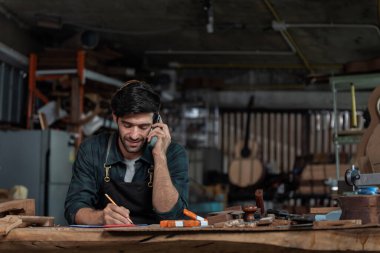 Gitar Luthier küçük işletme sahibi, müşteriden sipariş alan genç adam cep telefonu, sanat ve zanaat konsepti.
