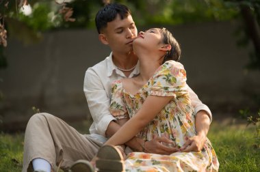 Asyalı genç çift birbirine bakıyor ve sarılıyorlar, erkek ve kadın birlikte vakit geçiriyorlar..