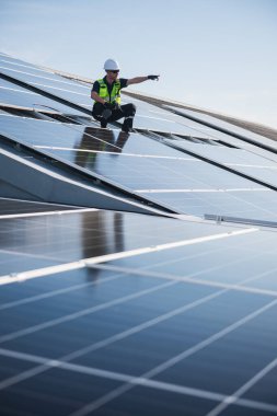 Teknisyen yeşil enerji için fabrikanın çatısına güneş panelleri kuruyor. Güvenlik teçhizatı konusunda yetenekli bir teknisyen çatıdaki bir güneş paneli tesisi üzerinde çalışıyor. Temiz enerji yenilenebilir enerji teknolojisi.